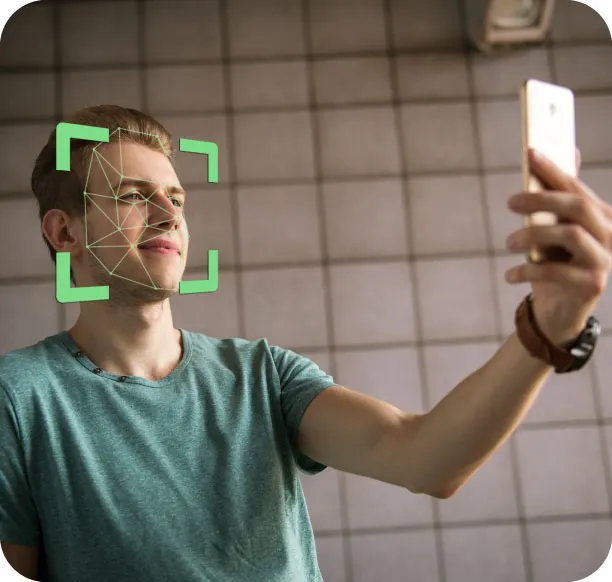 Hombre sosteniendo un teléfono mientras un recuadro de reconocimiento facial mapea su rostro